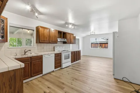 a large kitchen with stainless steel appliances granite countertop a sink dishwasher stove and wooden floor