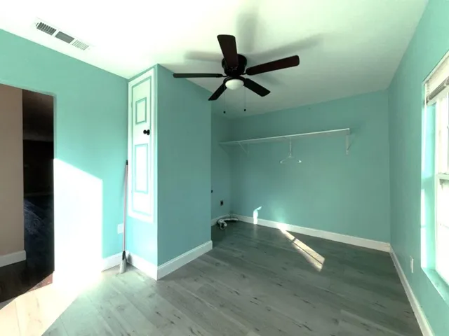 a view of empty room with wooden floor and fan