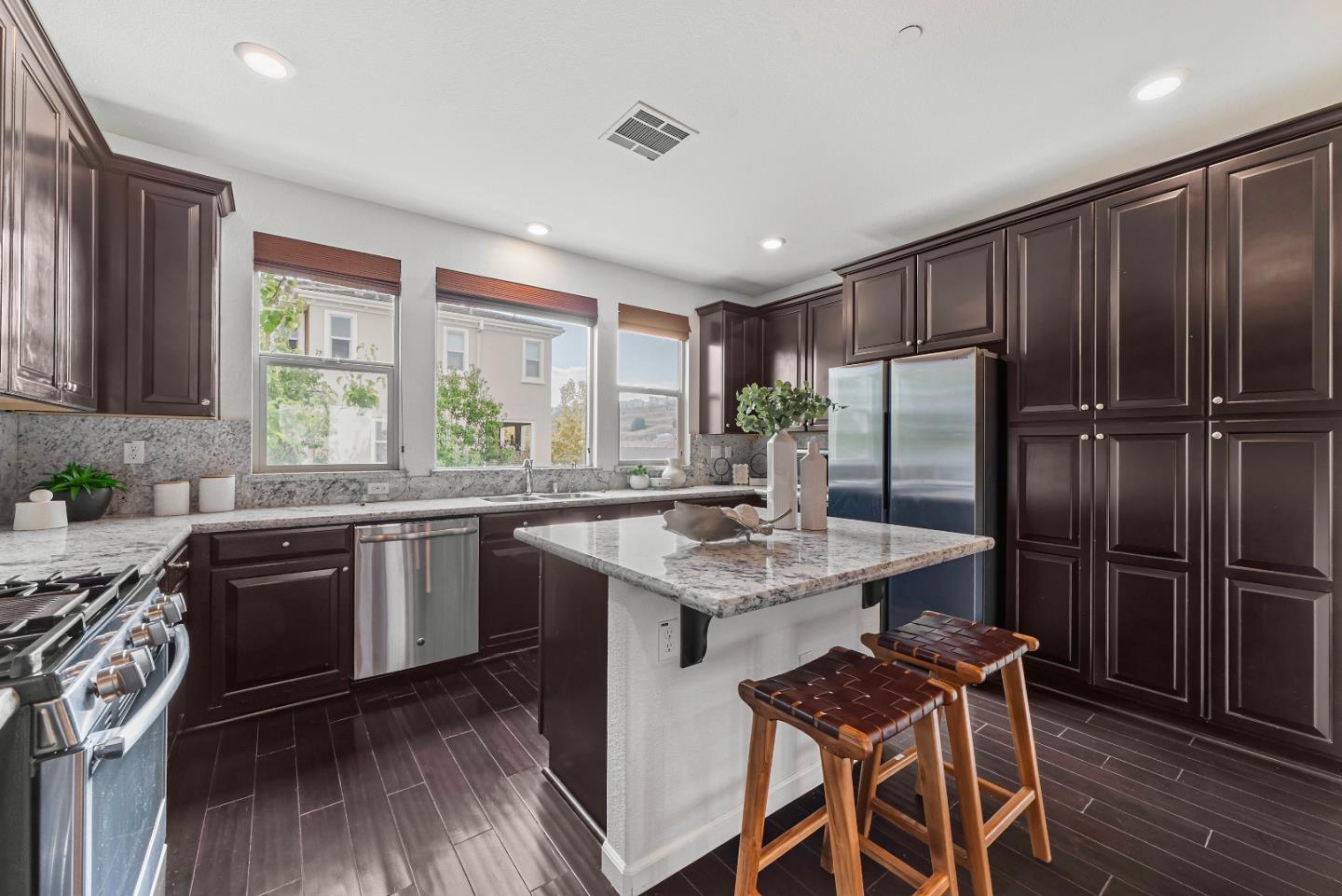 2753 Ferrara Circle San Jose, CA 95111 - Photo 10 of 46 a kitchen with stainless steel appliances granite countertop a stove a refrigerator a sink dishwasher a dining table and chairs with wooden floor