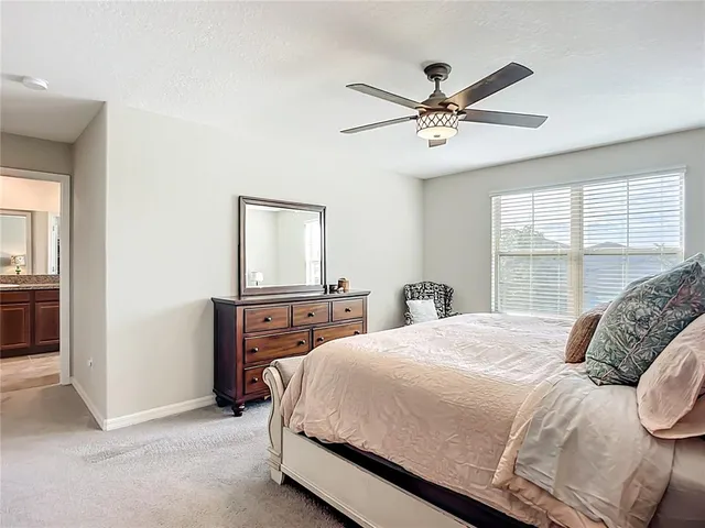 a bedroom with a bed next to a window with the desk and chair