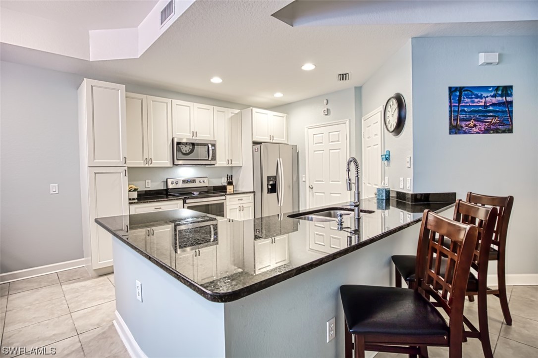 a kitchen with granite countertop kitchen island stainless steel appliances a sink counter space and a refrigerator