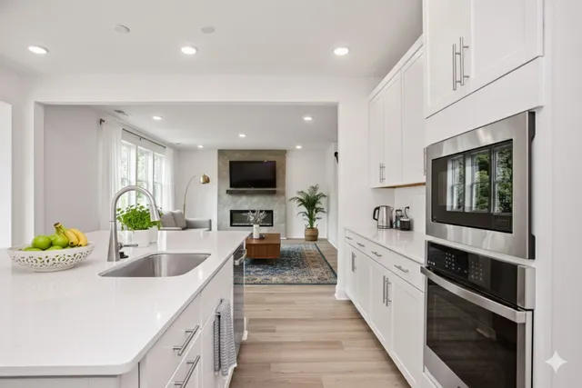 a large kitchen with kitchen island white cabinets and stainless steel appliances