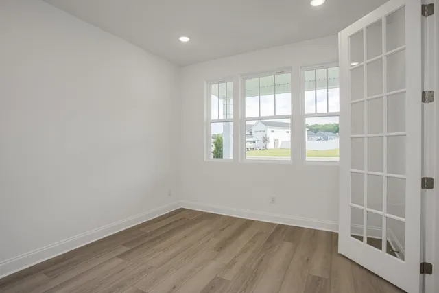 an empty room with wooden floor and windows