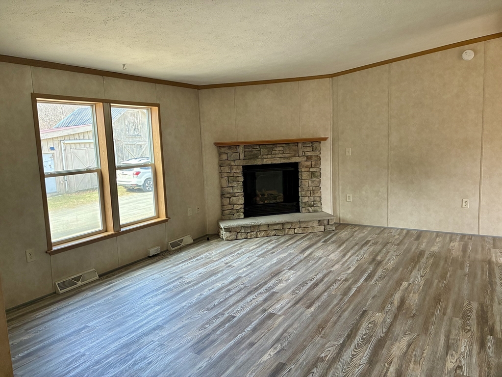 559 Tea Street, Unit 9 Charlemont, MA 01339 - Photo 12 of 21 an empty room with wooden floor fireplace and windows