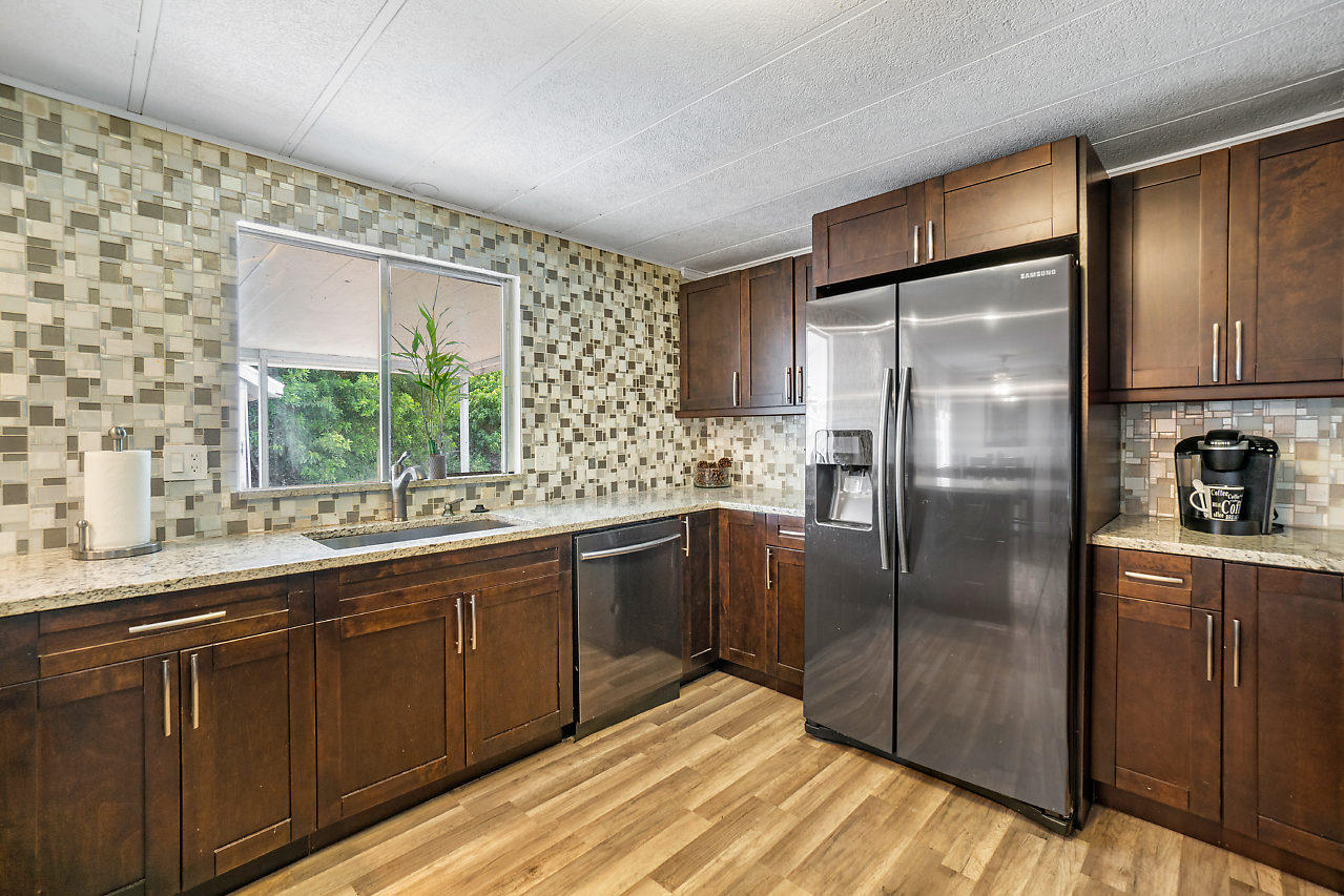 11941 Flotilla Place Boca Raton, FL 33428 - Photo 19 of 21 a kitchen with stainless steel appliances granite countertop a refrigerator a sink dishwasher a stove with wooden cabinets and floor