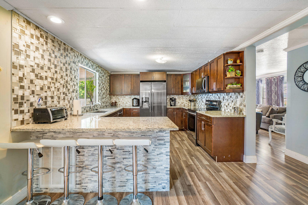 11941 Flotilla Place Boca Raton, FL 33428 - Photo 20 of 21 a kitchen with stainless steel appliances granite countertop a stove top oven a sink dishwasher a dining table and chairs with wooden floor