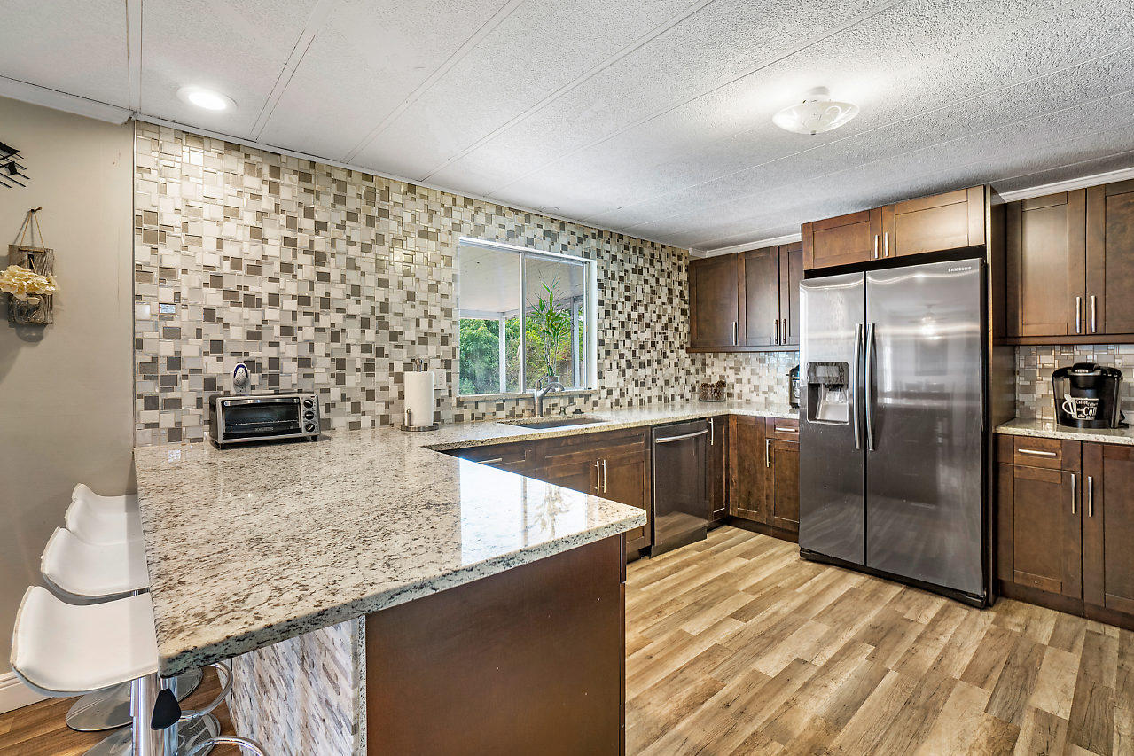 11941 Flotilla Place Boca Raton, FL 33428 - Photo 5 of 21 a kitchen with granite countertop a refrigerator a sink a stove and chairs