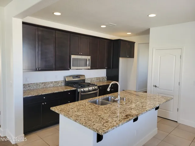 a kitchen with kitchen island granite countertop a sink a stove and refrigerator