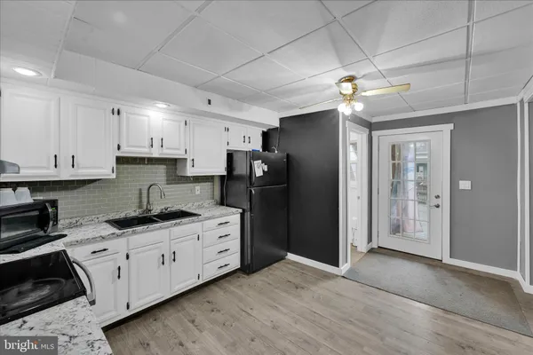 a kitchen with stainless steel appliances granite countertop a refrigerator a sink dishwasher a stove and white cabinets with wooden floor