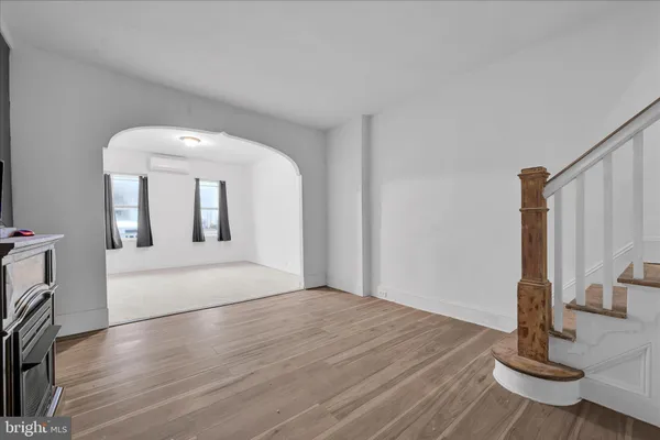 a view of an empty room with wooden floor fireplace and a window