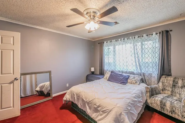 a bedroom with a bed desk and a flat screen tv
