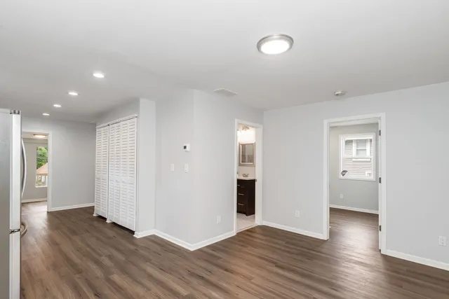 a view of an empty room with wooden floor and closet