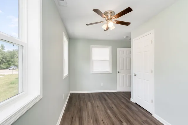 an empty room with wooden floor and windows