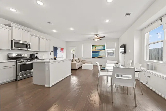 a living room with stainless steel appliances kitchen island a table and chairs