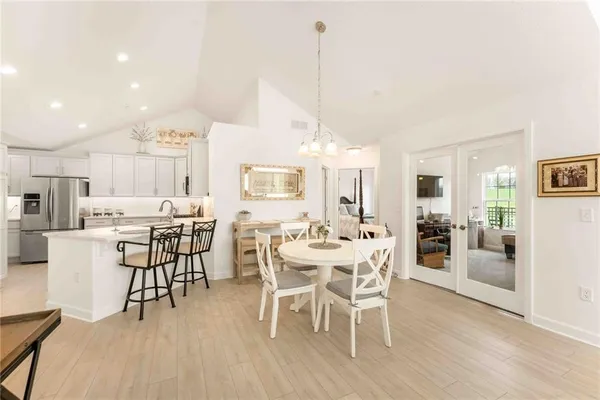 a view of a dining room and livingroom with furniture wooden floor a rug a flat screen tv a painting and a chandelier