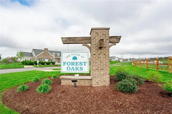 a sign board with a big yard and large trees