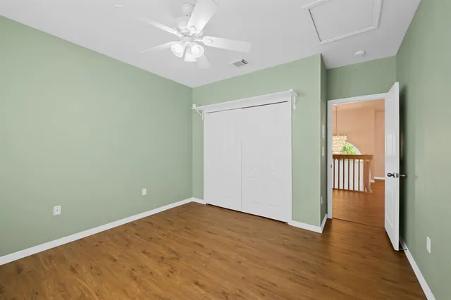 an empty room with wooden floor and a ceiling fan