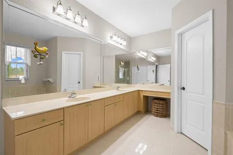 a spacious bathroom with a double vanity sink a mirror and a bathtub