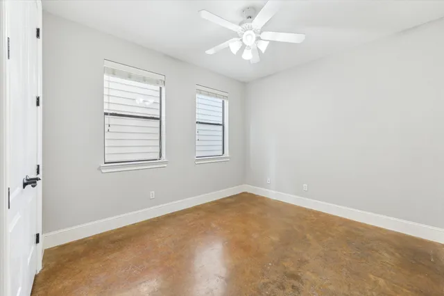 an empty room with windows and fan