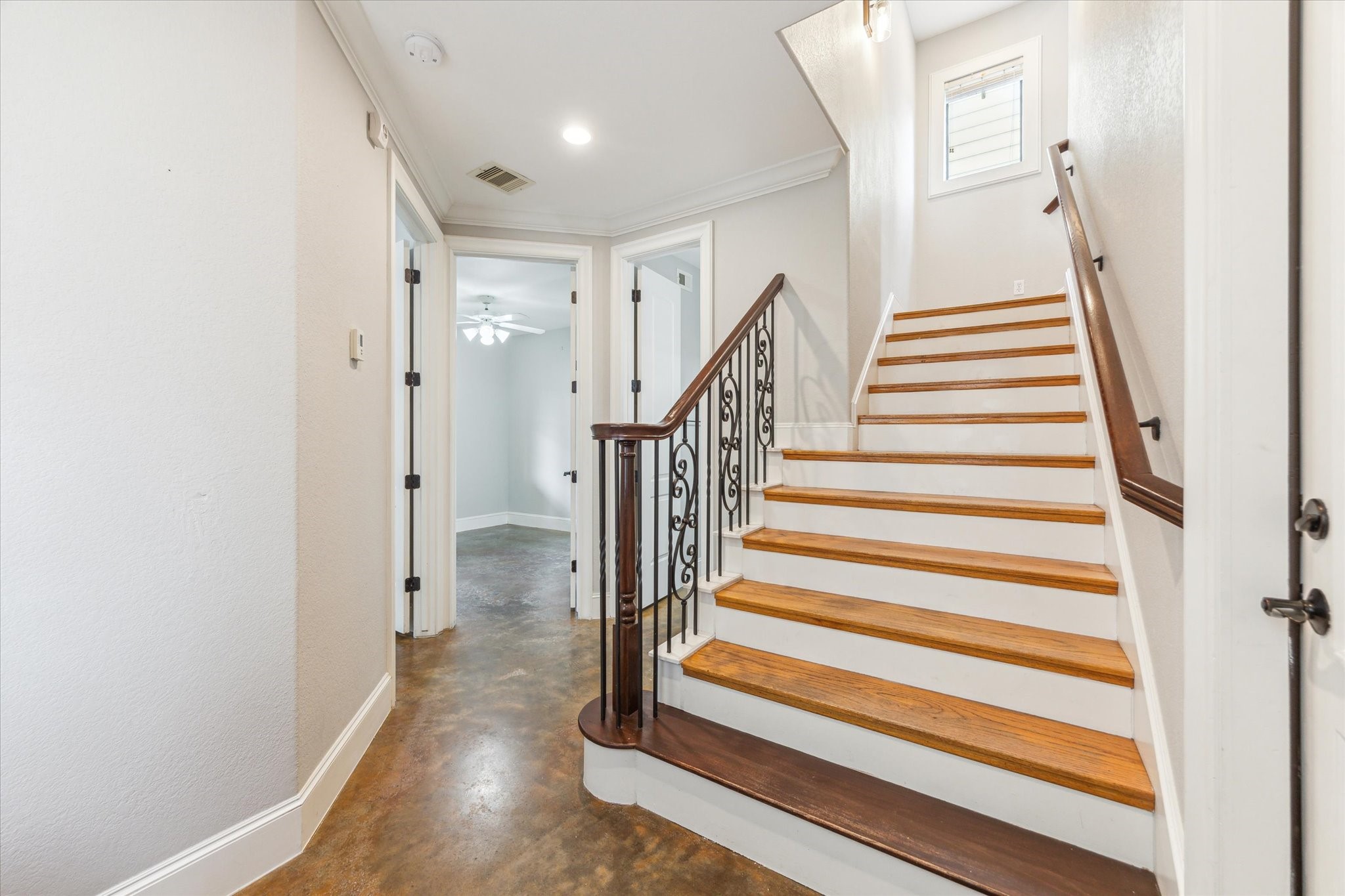 1512 Thompson Street, Unit 3 Houston, TX 77007 - Photo 10 of 32 A bright entry with polished wooden stairs featuring elegant wrought iron railings. The flooring is a warm, polished concrete, complementing the neutral wall tones.