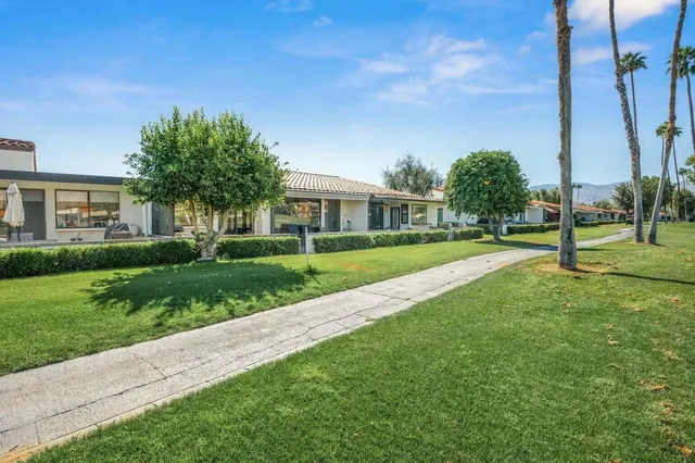 a view of a house with a big yard and palm trees