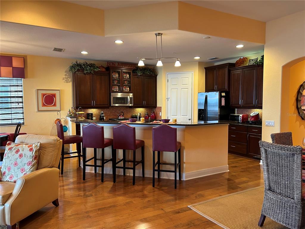 1139 Riverscape Street, Unit 1139 Bradenton, FL 34208 - Photo 11 of 45 a kitchen with stainless steel appliances kitchen island granite countertop a refrigerator a stove a sink and a dining table with wooden floor