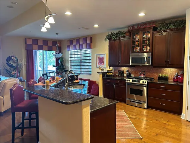 a kitchen with a stove a sink a refrigerator and chairs
