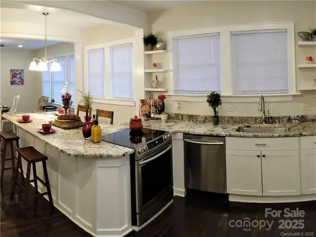 a kitchen with stainless steel appliances granite countertop a sink stove and cabinets