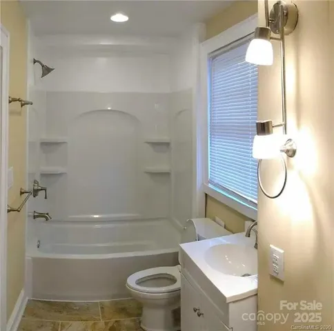 a bathroom with a granite countertop toilet sink and mirror