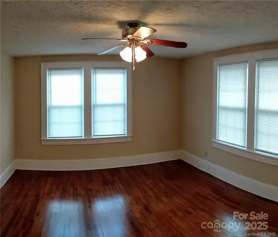 a view of wooden floor and a chandelier fan in a room