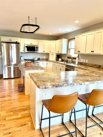 a kitchen with stainless steel appliances granite countertop a refrigerator a stove a sink dishwasher and white cabinets with wooden floor