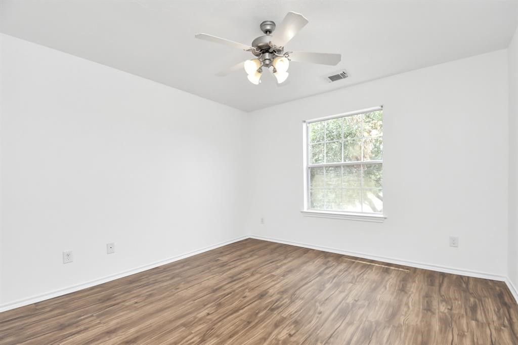 21818 Dimmett Way Spring, TX 77388 - Photo 26 of 35 an empty room with wooden floor chandelier fan and windows