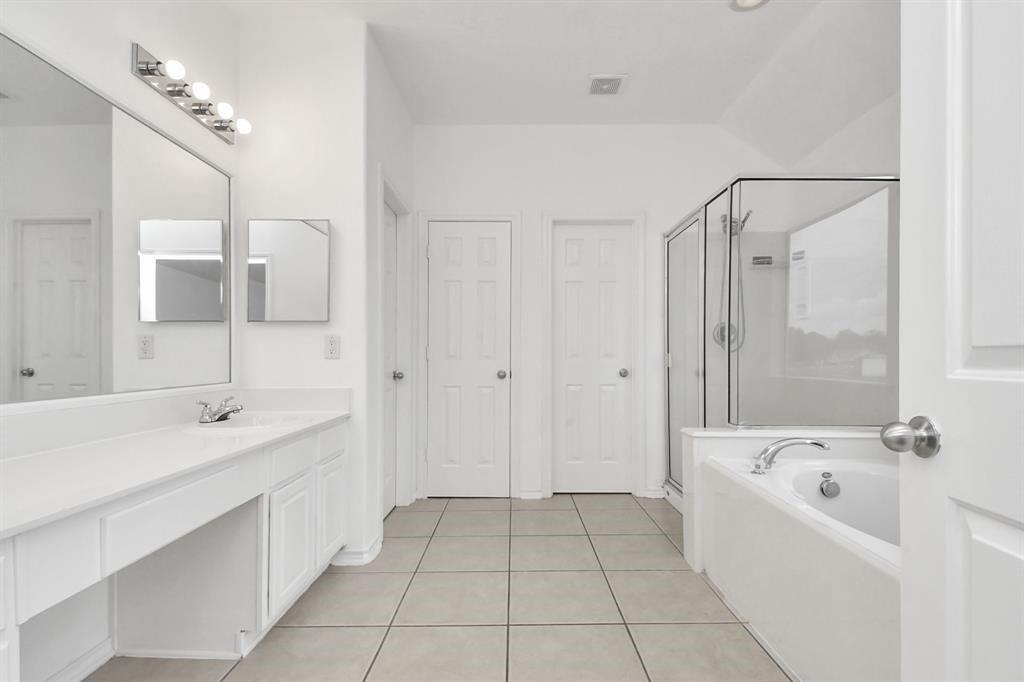 21818 Dimmett Way Spring, TX 77388 - Photo 30 of 35 a bathroom with a bathtub a sink a mirror and a shower