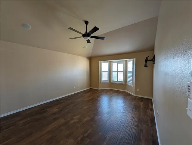 an empty room with wooden floor fan and windows