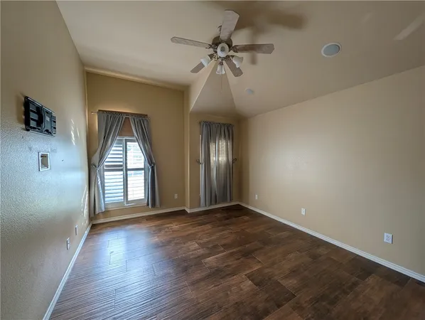 an empty room with wooden floor chandelier and glass door