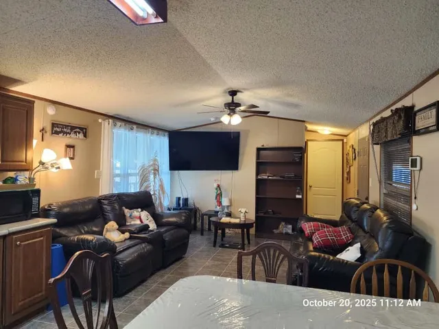 a living room with furniture a flat screen tv and kitchen view