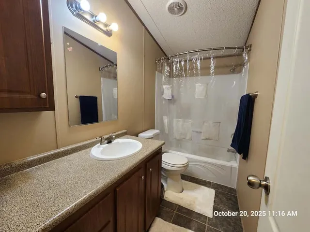 a bathroom with a granite countertop sink toilet mirror and shower