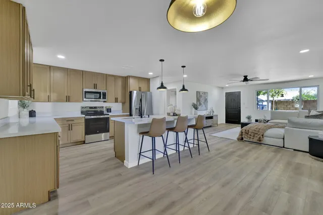 a kitchen with stainless steel appliances granite countertop a stove top oven a sink dishwasher a dining table and chairs with wooden floor