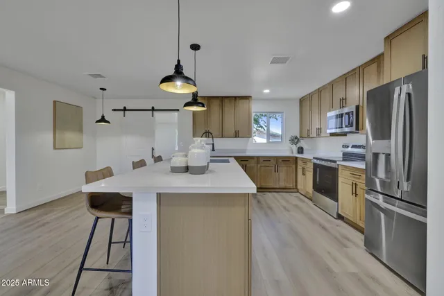 a kitchen with kitchen island a counter top space a sink stainless steel appliances and cabinets