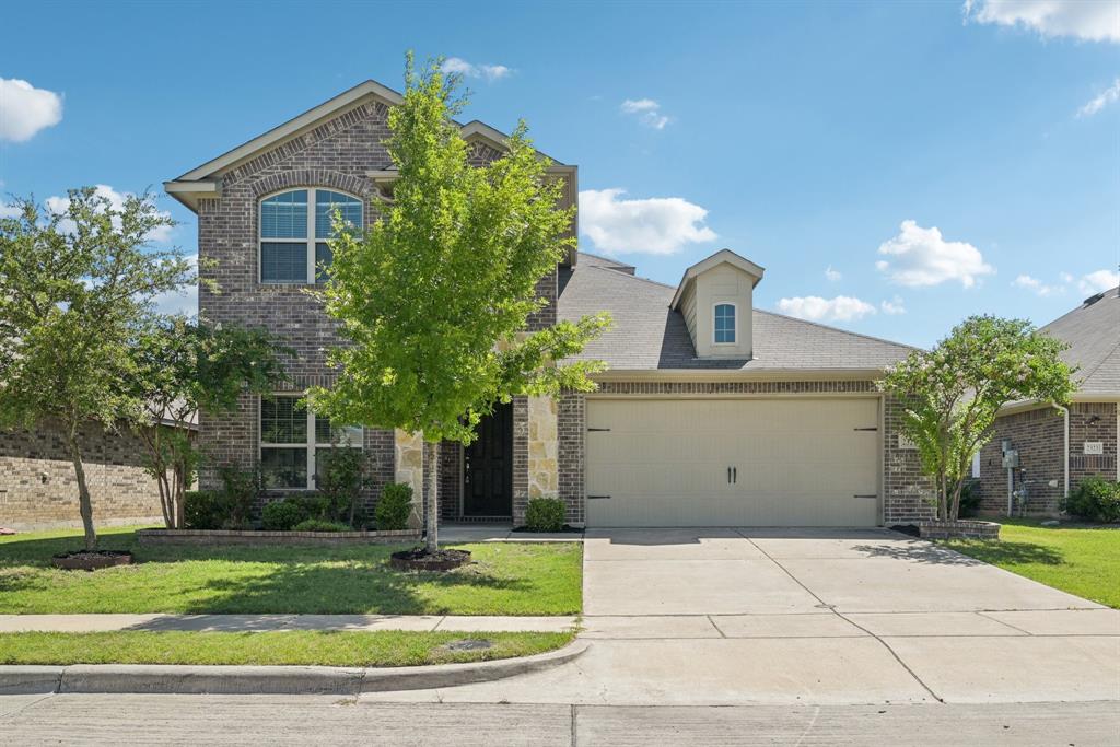 View of front of property with a garage, driveway, brick siding, and a front lawn