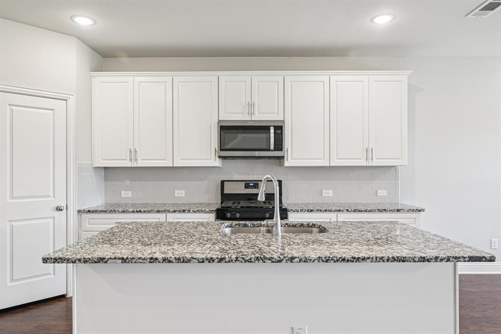 2321 Mount Olive Lane Forney, TX 75126 - Photo 13 of 35 Kitchen with dark wood-type flooring, stainless steel appliances, recessed lighting, light stone countertops, and white cabinets