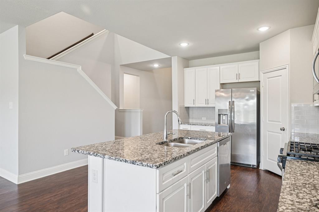 2321 Mount Olive Lane Forney, TX 75126 - Photo 15 of 35 Kitchen featuring tasteful backsplash, dark wood-style floors, appliances with stainless steel finishes, light stone countertops, and white cabinetry