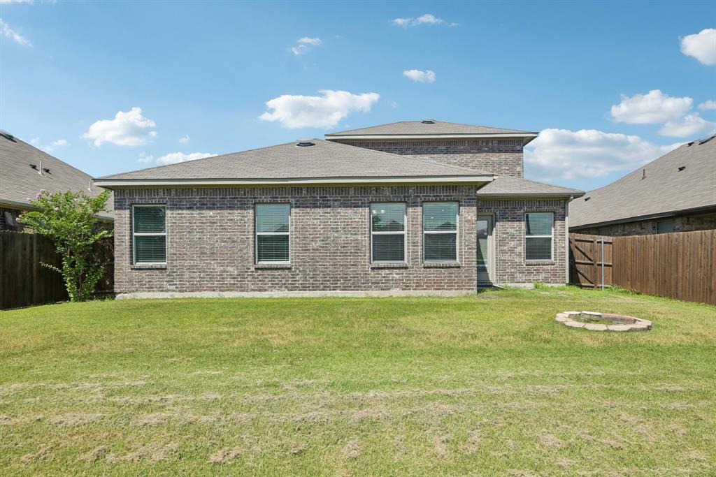 2321 Mount Olive Lane Forney, TX 75126 - Photo 34 of 35 Rear view of property with a fenced backyard, brick siding, roof with shingles, and a fire pit