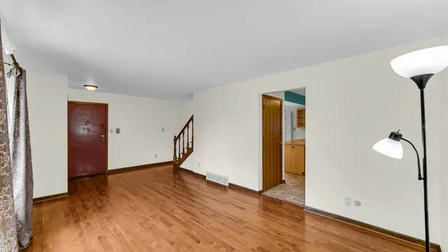 an empty room with wooden floor and windows