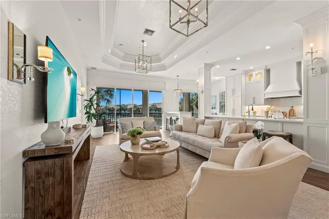 a living room with furniture kitchen view and a chandelier