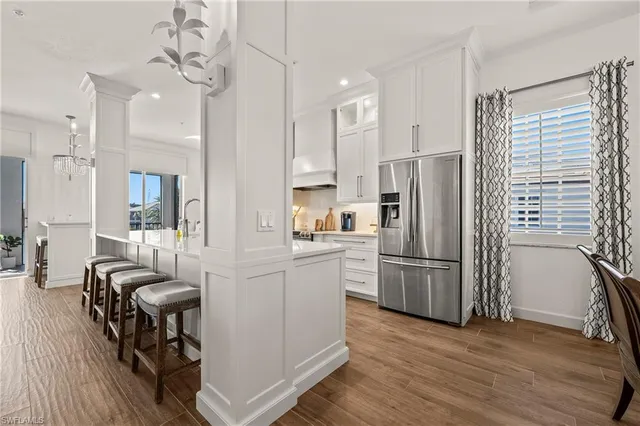 a kitchen with stainless steel appliances a refrigerator a stove a sink dishwasher a dining table and chairs with wooden floor