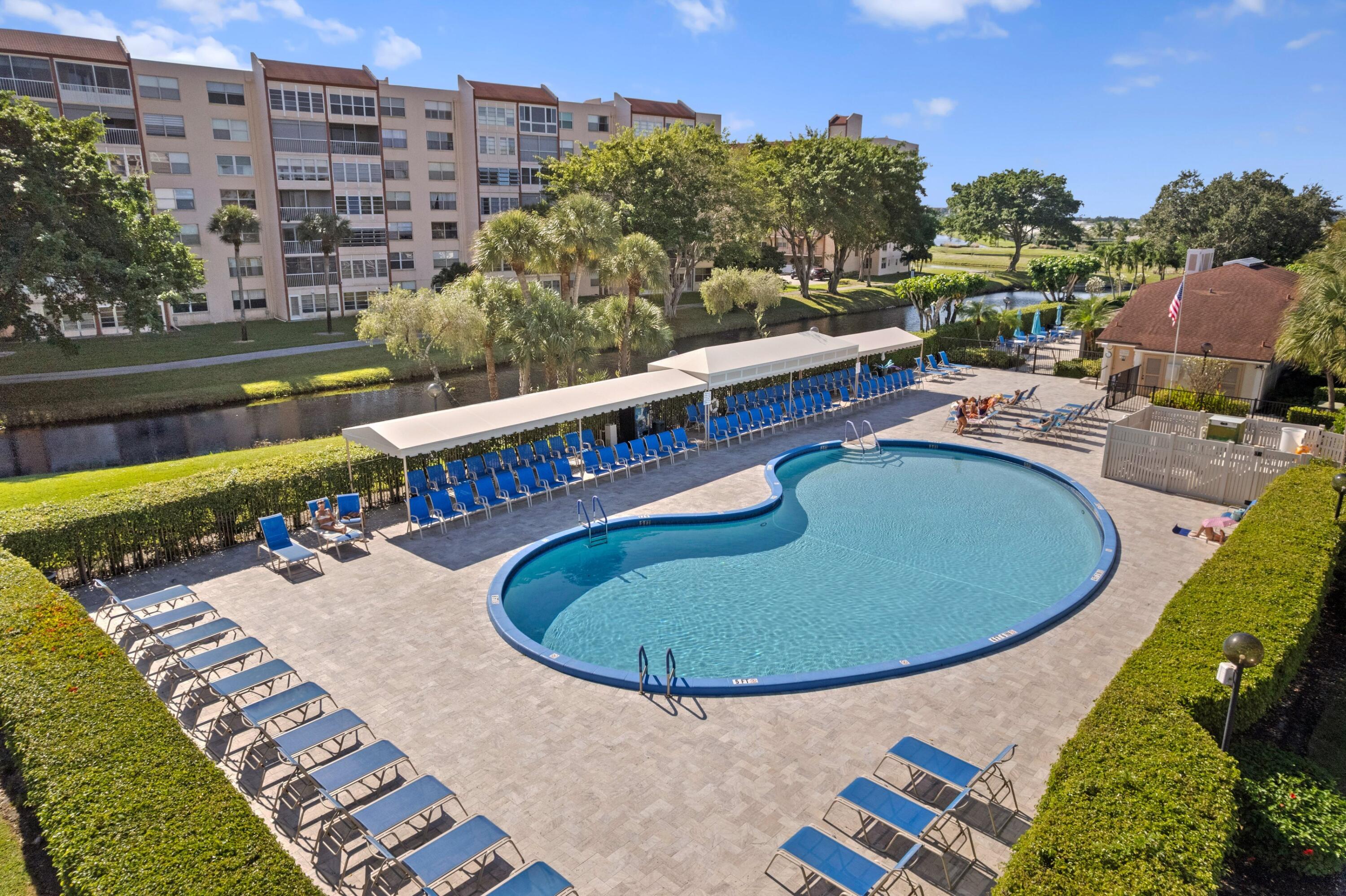 14360 Strathmore Lane, Unit 404 Delray Beach, FL 33446 - Photo 23 of 42 a view of a swimming pool with a chairs and table in the patio