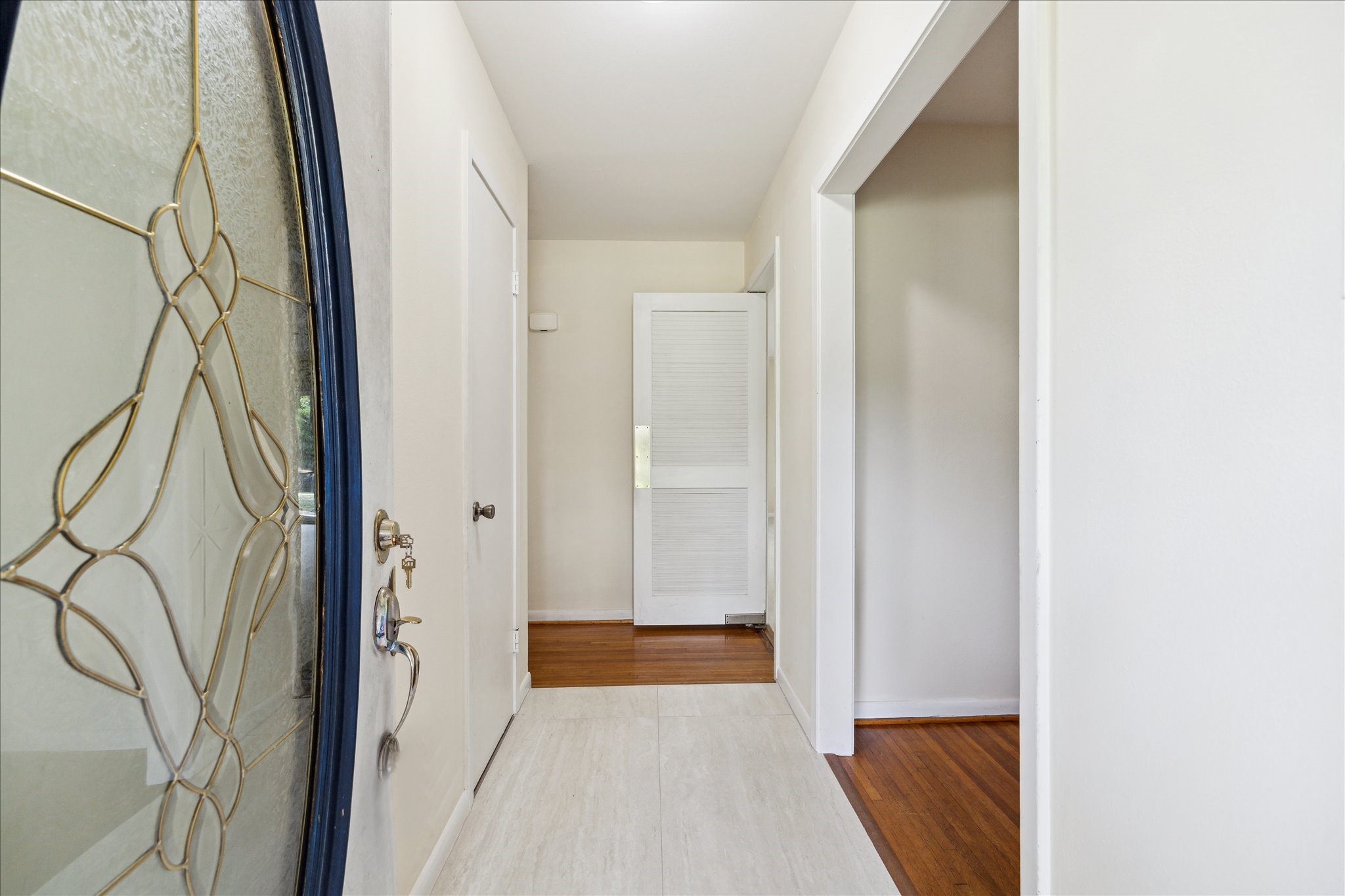 8907 Autauga Street Houston, TX 77080 - Photo 3 of 20 This photo shows a bright and welcoming entryway with a decorative glass front door, light-colored walls, and a mix of tile and wood flooring. The hallway leads to other parts of the home, offering a clean and modern feel.