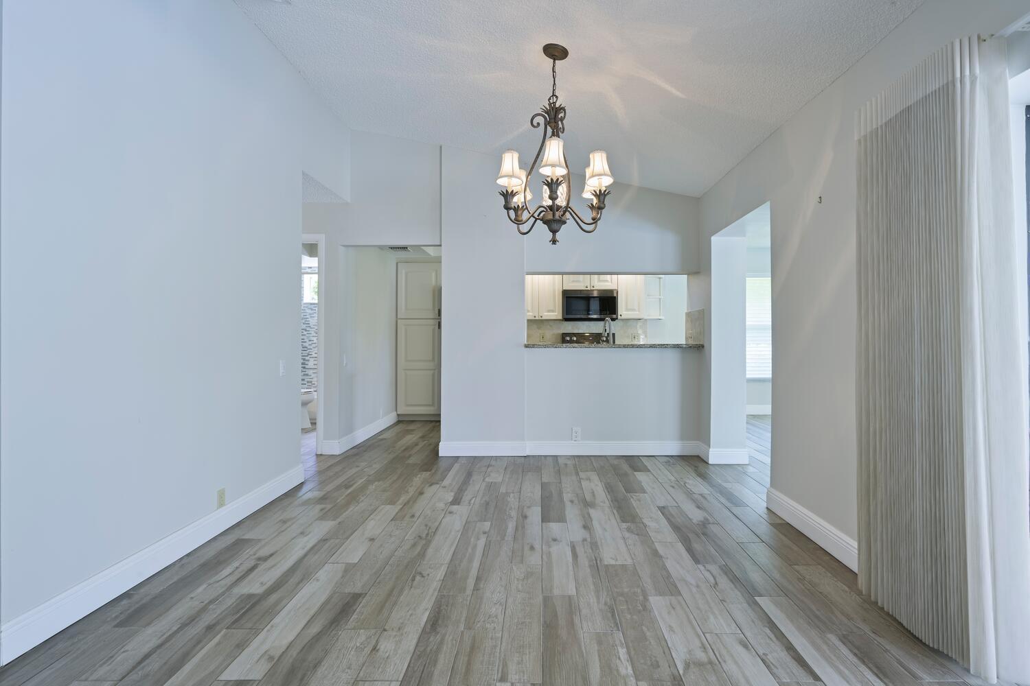 166 Bayberry Circle Jupiter, FL 33458 - Photo 12 of 37 a view of a hallway with wooden floor and a kitchen