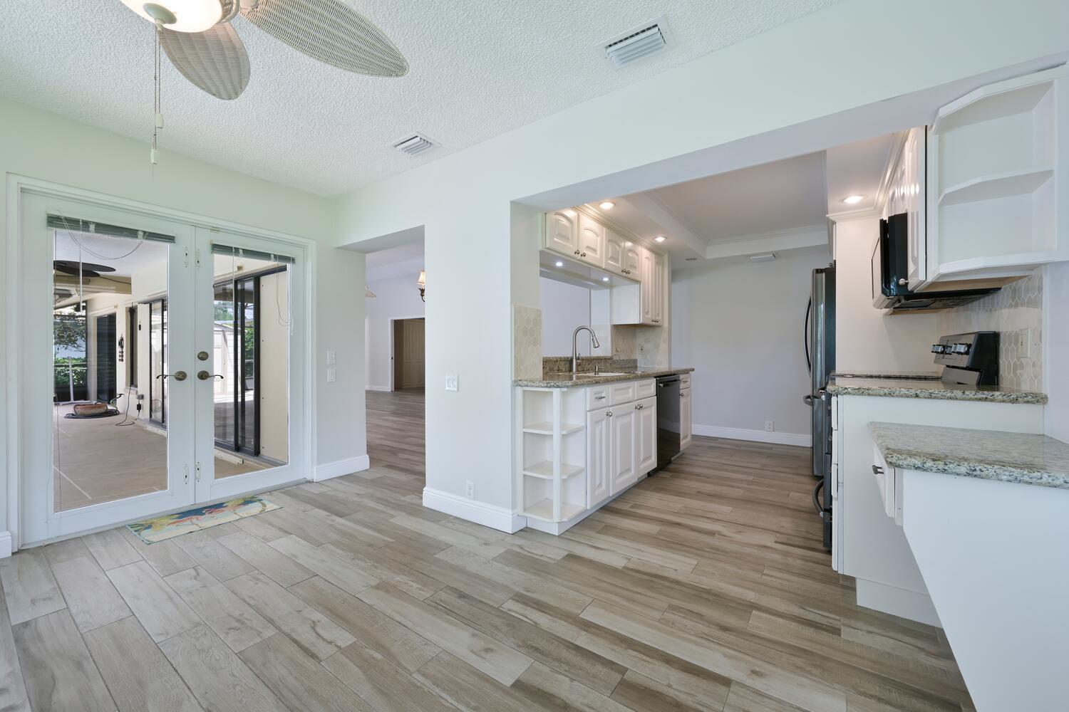 166 Bayberry Circle Jupiter, FL 33458 - Photo 15 of 37 a large kitchen with stainless steel appliances granite countertop a refrigerator a stove a sink dishwasher and white cabinets with wooden floor